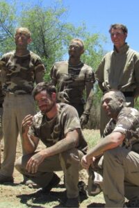 Group of volunteers and rangers covered in camouflage during outdoor field training in Namibia