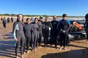 Group of marine conservation volunteers in wetsuits on the beach in Sodwana Bay, South Africa, before a reef monitoring session
